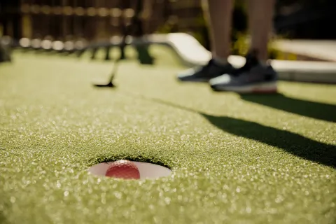 Spelar minigolf.